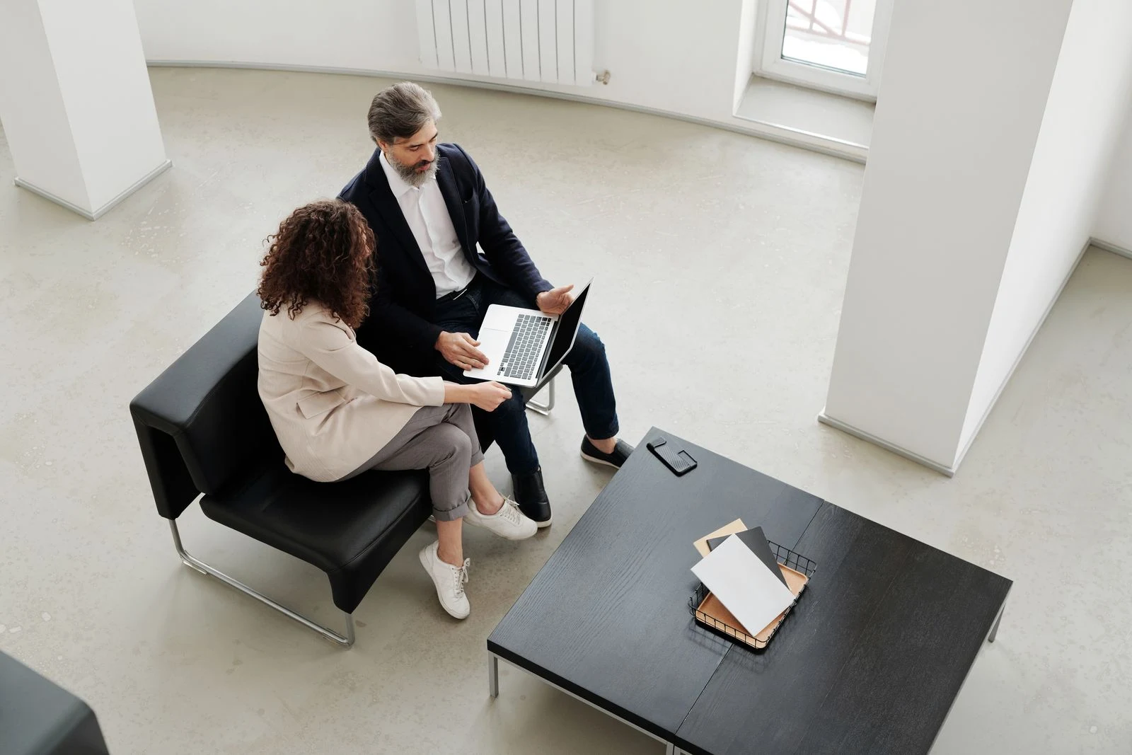 Two professionals discussing work with a laptop in a bright office